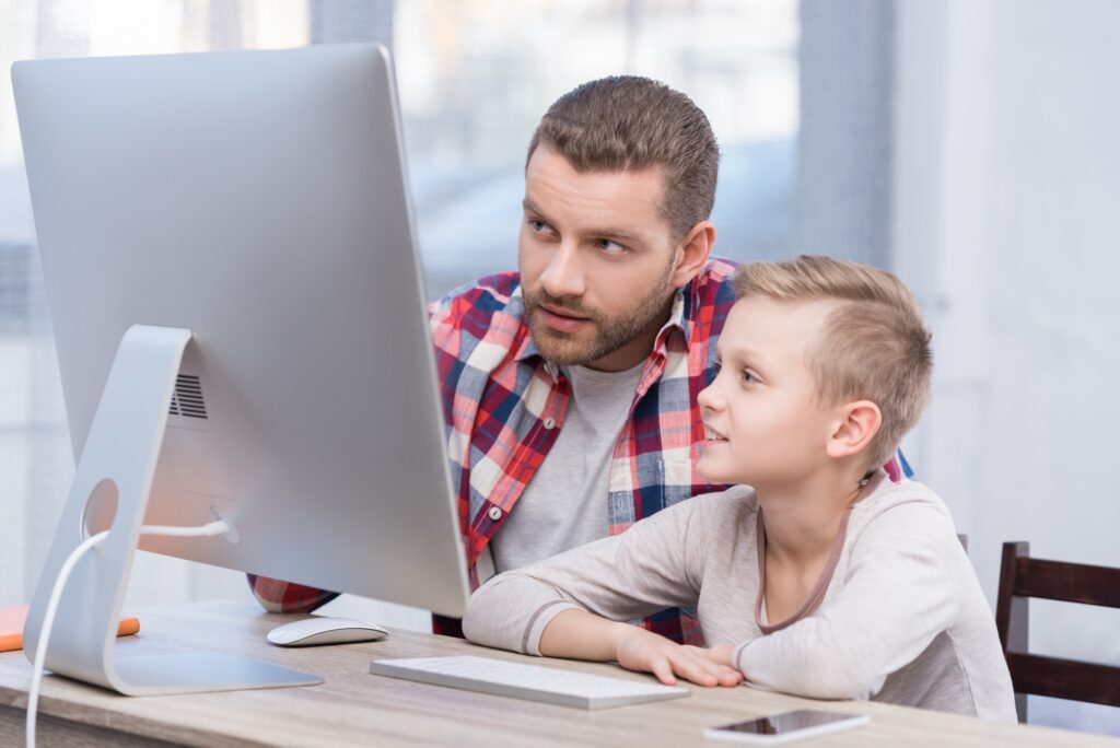 focused father and son using desktop computer together